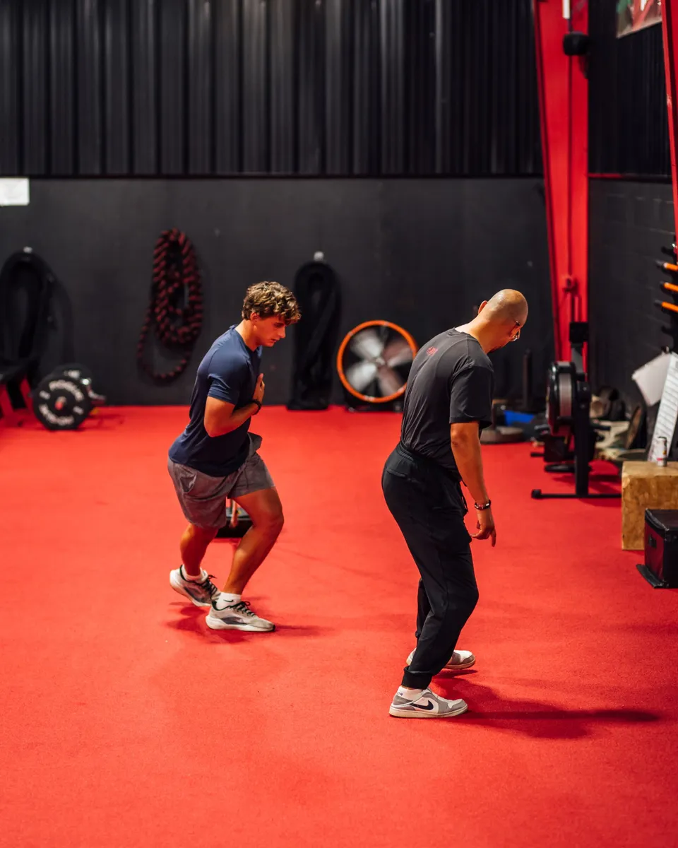 Tim Merolillo, owner and head trainer at Elite Custom Fitness, guiding a golfer through a movement drill